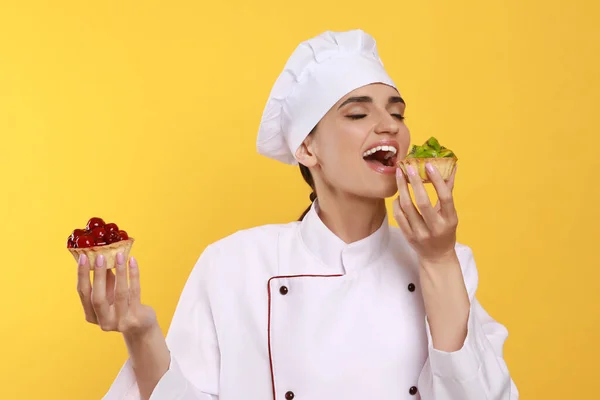 Pasticceria Professionale Uniforme Con Deliziose Tortine Fondo Giallo — Foto Stock