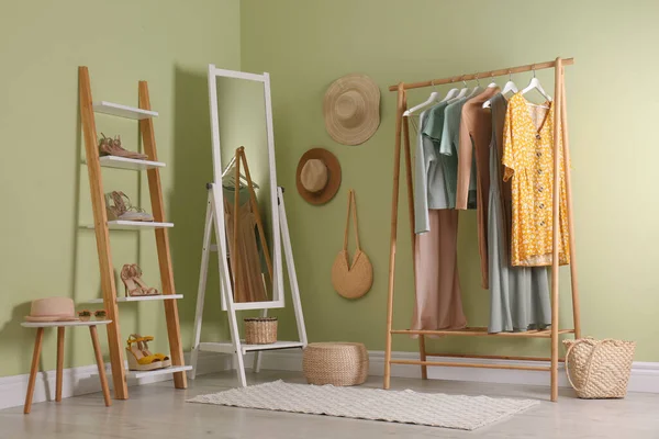 Modern dressing room interior with clothing rack and mirror near light green wall