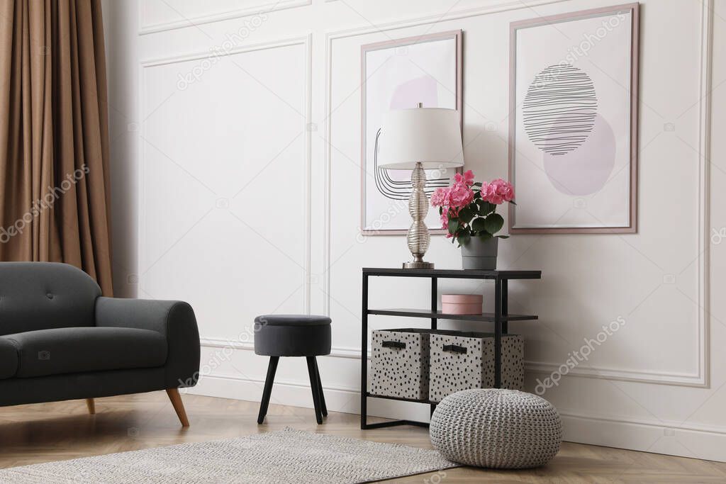 Console table with beautiful hydrangea flower and lamp near white wall in room. Interior design