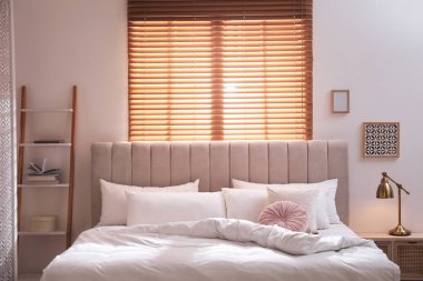 Işık odasında yumuşak çarşaflı rahat bir yatak.