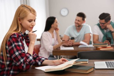 Öğrenciler kütüphanede kitap okuyor ve okuyor.