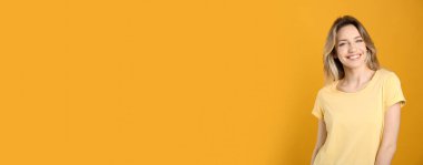 Sarı arka planda güzel sarı saçları ve büyüleyici gülüşü olan mutlu genç bir kadının portresi. Metin için boşluk