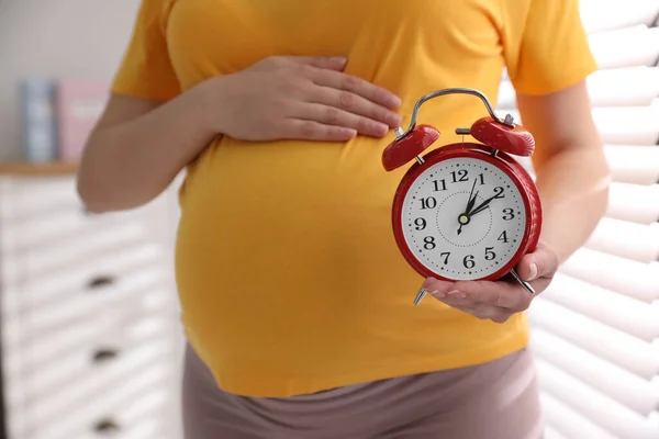 自宅近くで目覚まし時計を持っている若い妊婦は クローズアップ 出産までの時間 — ストック写真
