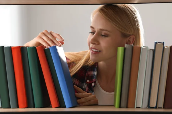 Woman searching for book on shelf in library