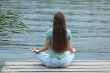 Genç bir kız nehrin kenarında meditasyon yapıyor.