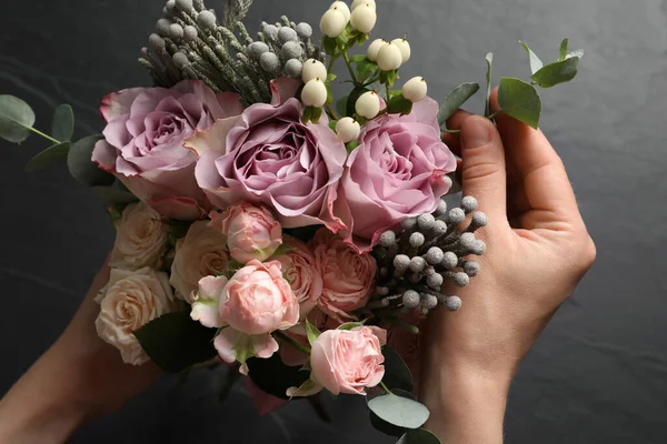 Florist creating beautiful bouquet at black table, top view