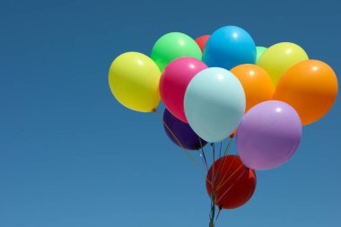 Mavi gökyüzüne karşı bir demet renkli balon