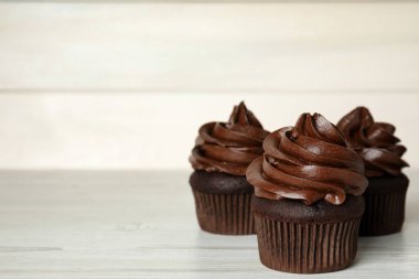 Beyaz ahşap masada kremalı lezzetli çikolatalı kekler. Metin için boşluk