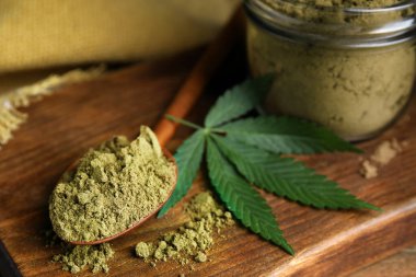 Hemp protein tozu ve tahta üzerinde taze yaprak, yakın plan.