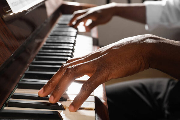 Афроамериканец играет на пианино в помещении, крупным планом. Талантливый музыкант