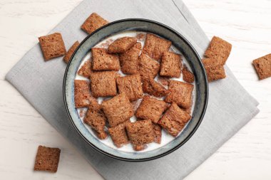 Lezzetli mısır gevrekleri ve beyaz ahşap masa üzerinde süt dolu bir kâse.