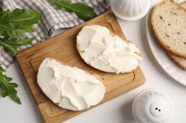 Beyaz ahşap masada krem peynirli ekmek.