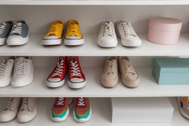 Renkli spor ayakkabı koleksiyonu olan beyaz raf ünitesi