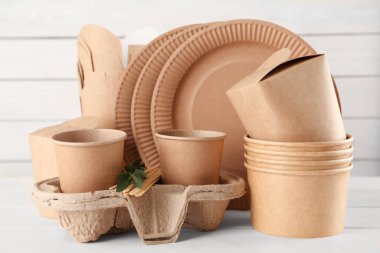 Tek kullanımlık çevre dostu ürünler beyaz ahşap masada.