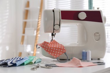 İçerideki masada kumaş maskeli dikiş makinesi.