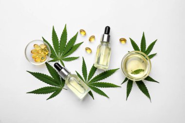 Beyaz zemin üzerinde kenevir yaprakları, CBD yağı ve THC tentürü ile düz konum