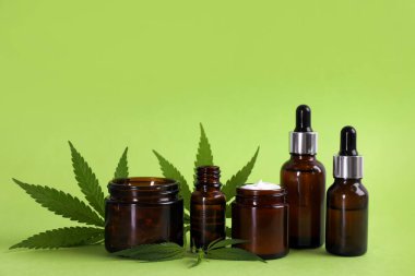 Açık yeşil zemin üzerinde CBD yağı, THC tentür ve kenevir yaprakları bileşimi