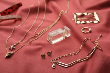 Şık altın bijouterie ve kırmızı kumaşta parfüm