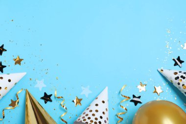 Düz kompozisyon, parti şapkaları, balon ve açık mavi arka planda konfeti, mesaj için boşluk. Doğum günü dekoru