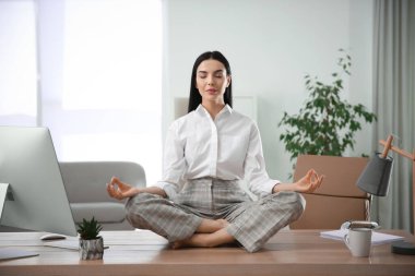 Genç bir kadın işyerinde meditasyon yapıyor. Stres atma egzersizi.