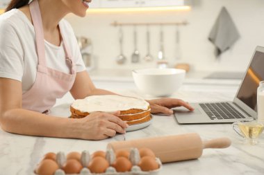 Mutfakta dizüstü bilgisayarla yemek kursunu izlerken pasta yapan kadın, yakın plan.