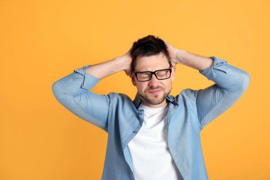 Sarı arka planda korkunç migren ağrısı çeken bir adam.