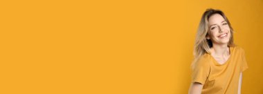 Sarı arka planda güzel sarı saçları ve büyüleyici gülüşü olan mutlu genç bir kadının portresi. Metin için boşluk