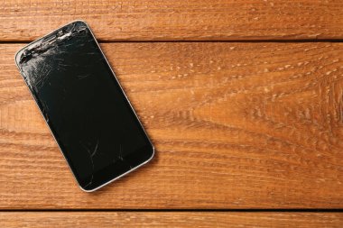 Tahta masadaki hasarlı akıllı telefon, yazı için yeri olan üst görünüm. Aygıt onarımı