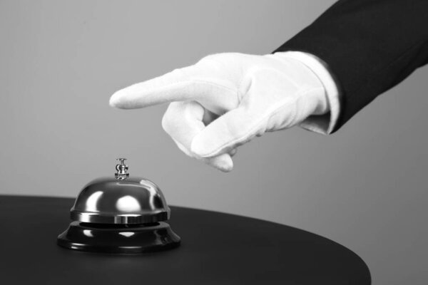 Butler ringing service bell at table, closeup