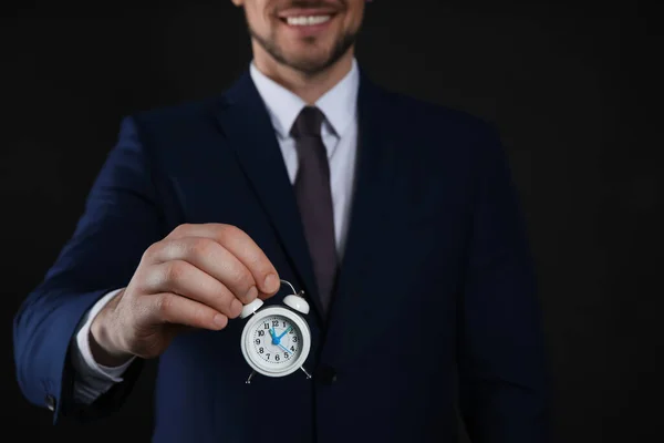 Feliz Hombre Negocios Sosteniendo Diminuto Despertador Sobre Fondo Negro Primer —  Fotos de Stock