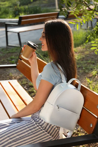 Красивая Молодая Женщина Стильным Рюкзаком Чашкой Кофе Скамейке Парке — стоковое фото