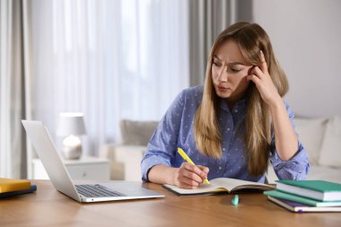 Odada Webinar izleyen kafası karışmış genç bir kadın.