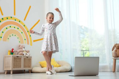 Sevimli küçük kız evde online dans dersi alıyor.