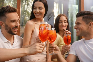Arkadaşlar açık kafede Aperol spritz kokteyli içiyorlar.