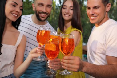 Arkadaşlar açık havada Aperol spritz kokteyli içiyorlar.