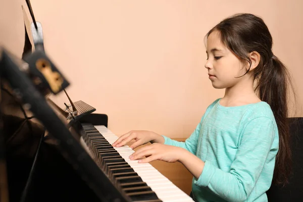 在米色墙边弹钢琴的小女孩很可爱 音乐课 — 图库照片