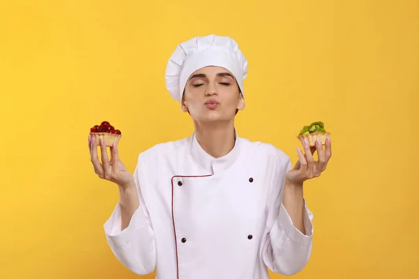 Pasticceria Professionale Uniforme Con Deliziose Tortine Fondo Giallo — Foto Stock