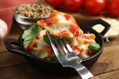 Ahşap masada servis edilen domates soslu ravioli, yakın plan.