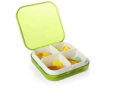 Beyaz üzerinde farklı haplar bulunan plastik kutu.