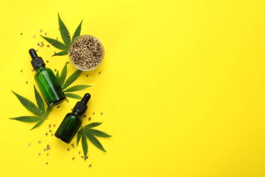 CBD yağı, THC tentürü, kenevir yaprakları ve sarı arka planda tahıllar, düz zemin. Metin için boşluk