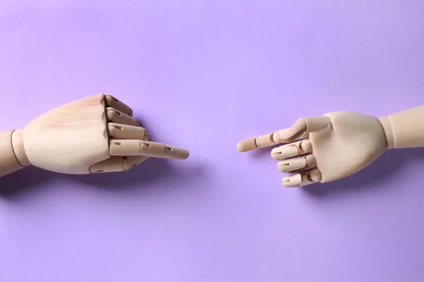 Wooden mannequin hands on lilac background, flat lay