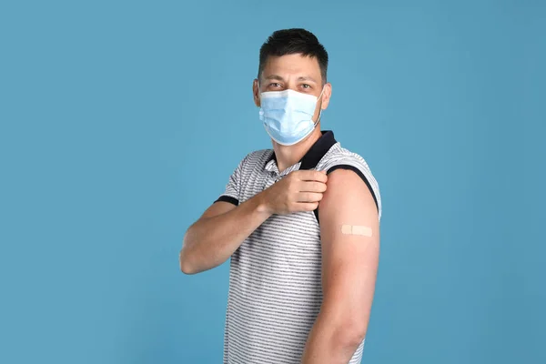 Вакцинация Мужчины Защитной Маске Показывает Медицинскую Штукатурку Руке Светло Голубом — стоковое фото