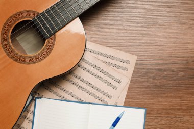 Tahta masa üzerinde gitar ve müzik notaları ile kompozisyon, düz yatıyordu