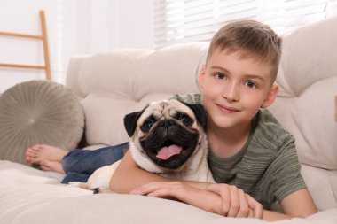 Evdeki kanepede tatlı köpeğiyle oturan çocuk.