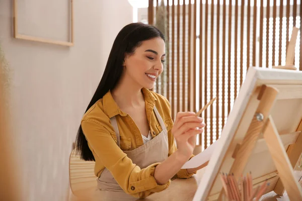 年轻女子在画架上画画 桌上有铅笔 — 图库照片
