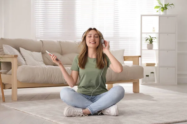 Oturma Odasında Yerde Oturmuş Müzik Dinleyen Kulaklıklı Genç Bir Kadın — Stok fotoğraf