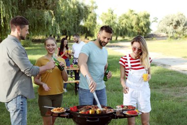 Bir grup arkadaş parkta barbekü partisi veriyor.