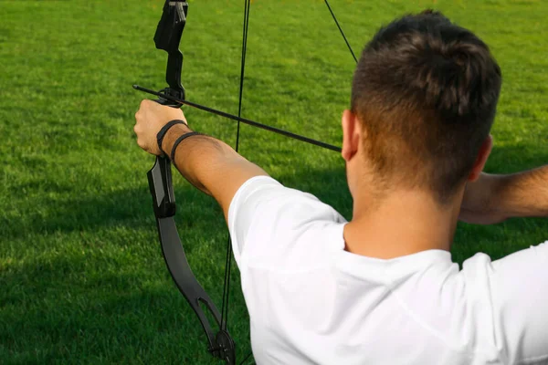 弓と矢を練習している男緑の芝生の上で弓 バックビュー ストックフォト