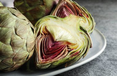 Gri masada taze çiğ enginarlar var. Yakın plan.