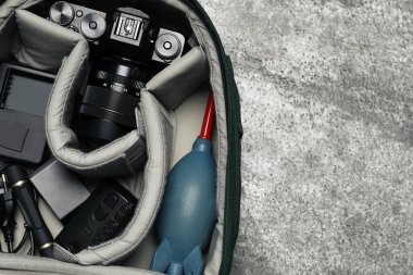 Gri taş masada sırt çantasında profesyonel fotoğraf ekipmanları, üst manzara. Metin için boşluk